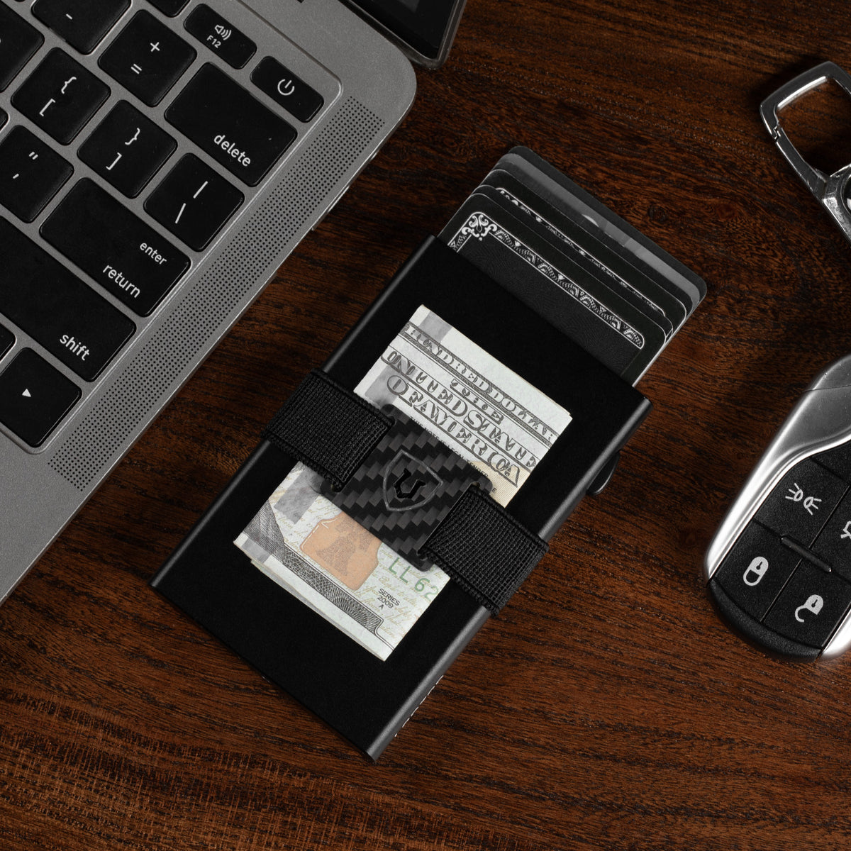 Black RFID-blocking wallet on a desk holding cards and folded cash under the strap
