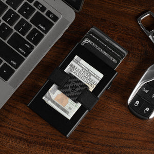 Black RFID-blocking wallet on a desk holding cards and folded cash under the strap