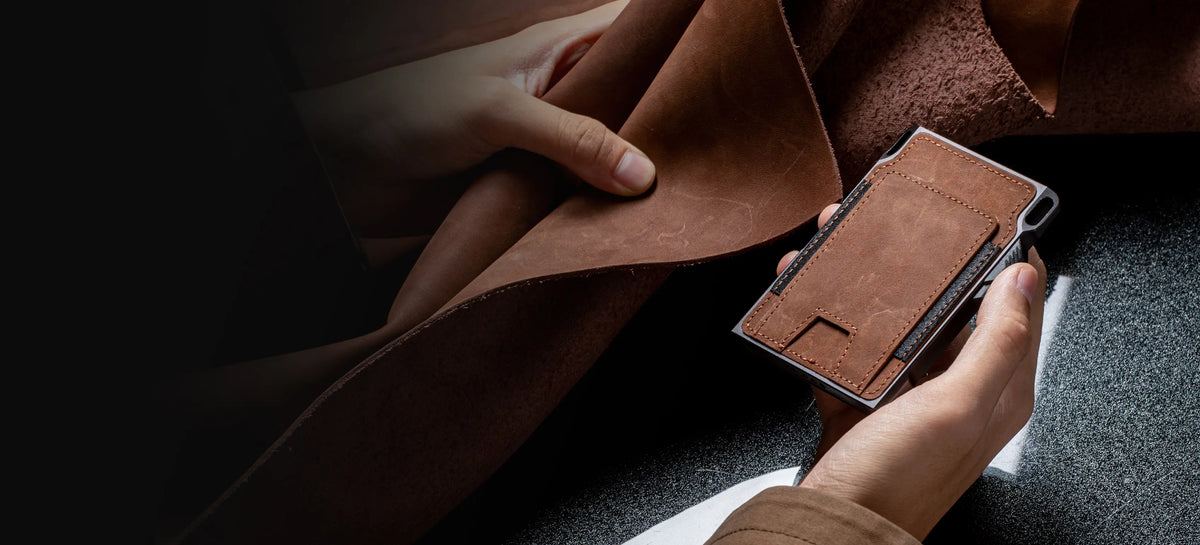 Wide homepage image showing a brown 1979 wallet in hand while full-grain leather is displayed beside it, with open space for accompanying brand copy.
