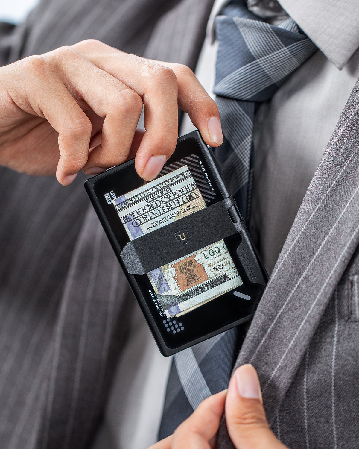 Black wallet worn against a suit jacket with banknotes visible through the front opening.