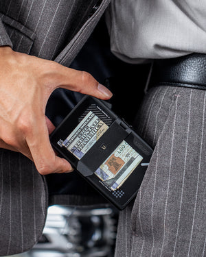 Wallet partially pulled from a suit pocket with folded banknotes secured under the external money strap.