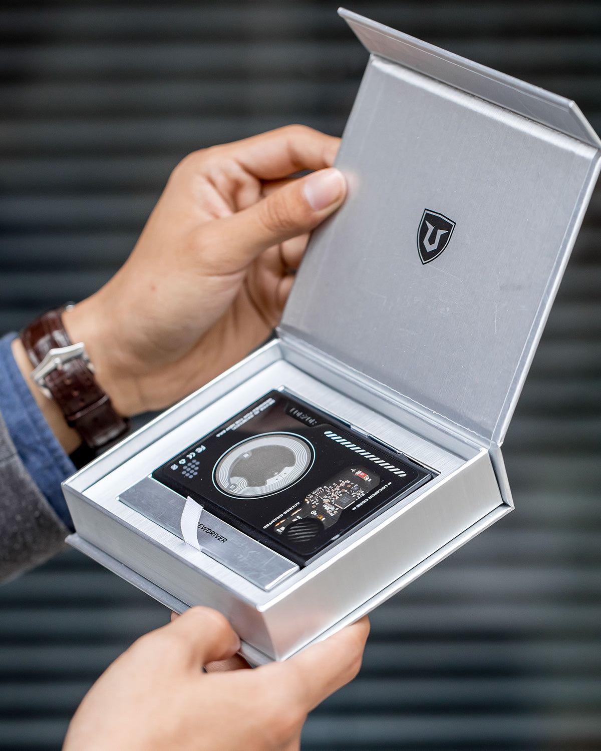 Opened presentation box displaying the wallet placed in a fitted insert with included accessories arranged inside.