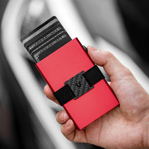 Red aluminum RFID wallet held in hand with cards extended and a black cash strap